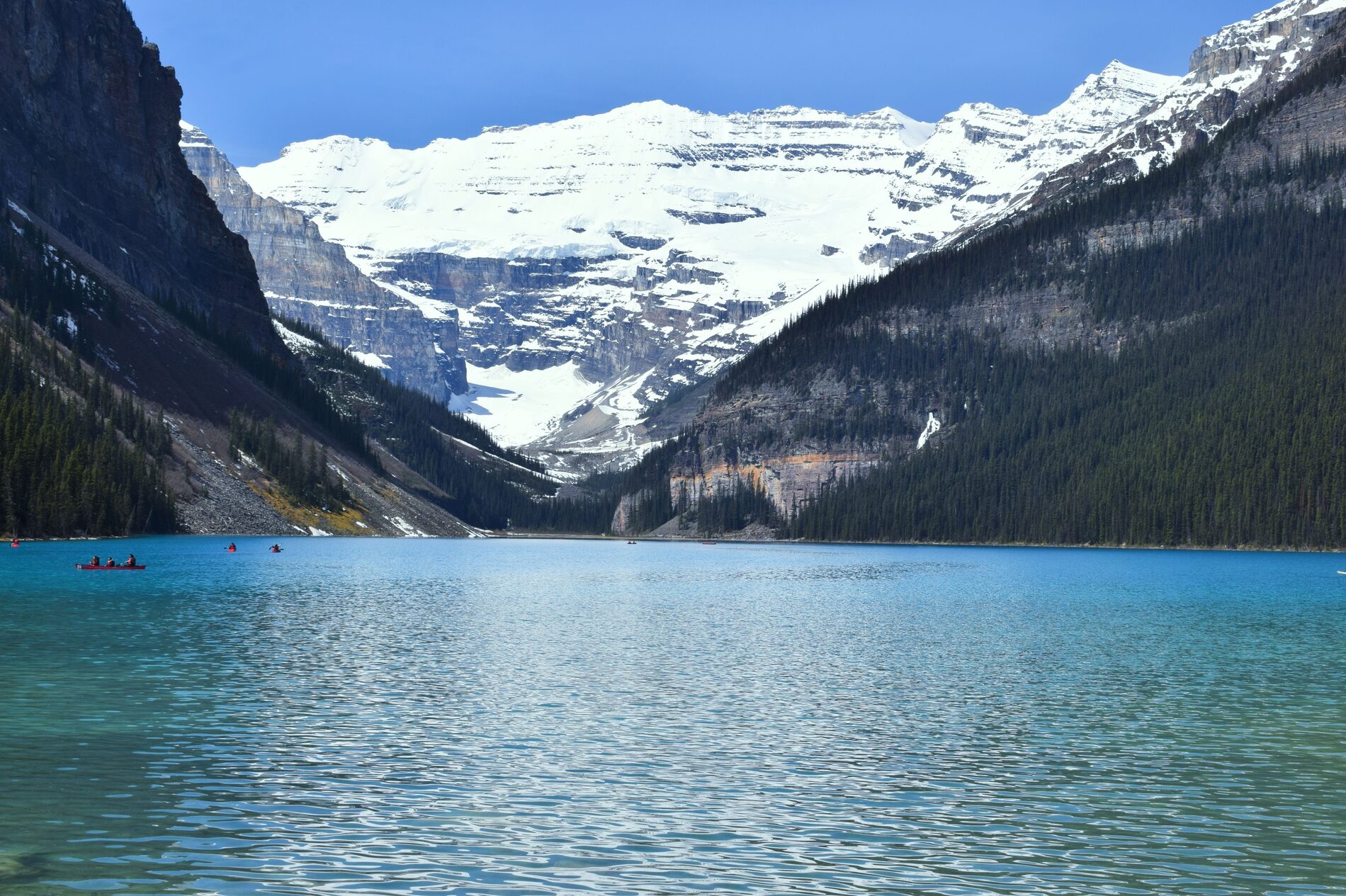 Turquoise Lake Louise below a snow-capped glacier and forested mountains
